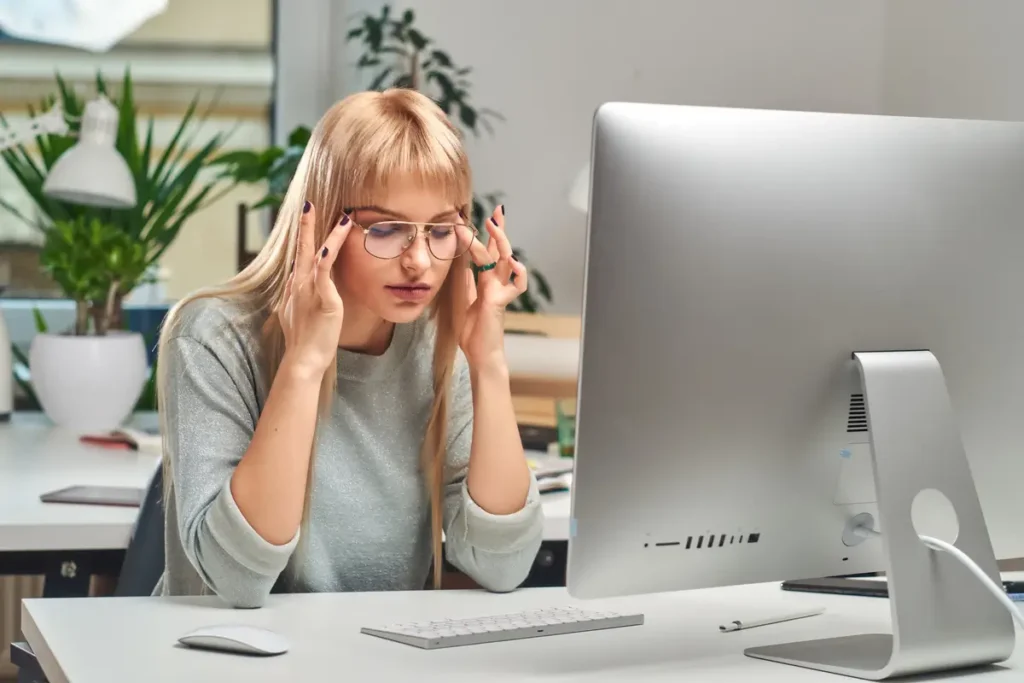 Persona con dolor de cabeza por tensión frente al computador